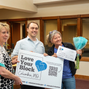 Neighborhood Services Manager Leigh Kottwitz and Jacob Richardson of Volunteer Programs present a Love Your Block grant plus a bouquet of flowers to Shelly Mayer, Executive Director of ForColumbia. Photo provided courtesy of the City Manager's Office.